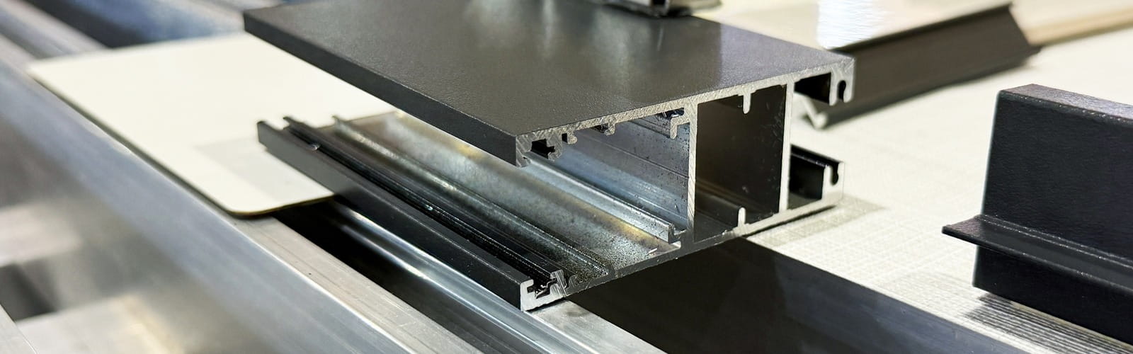 Cross-section of an anthracite grey aluminium trim profile showing its hollow extruded chambers