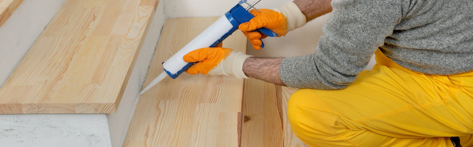 Applying a bead of fixing adhesive along a timber stair tread before fitting an aluminium nosing